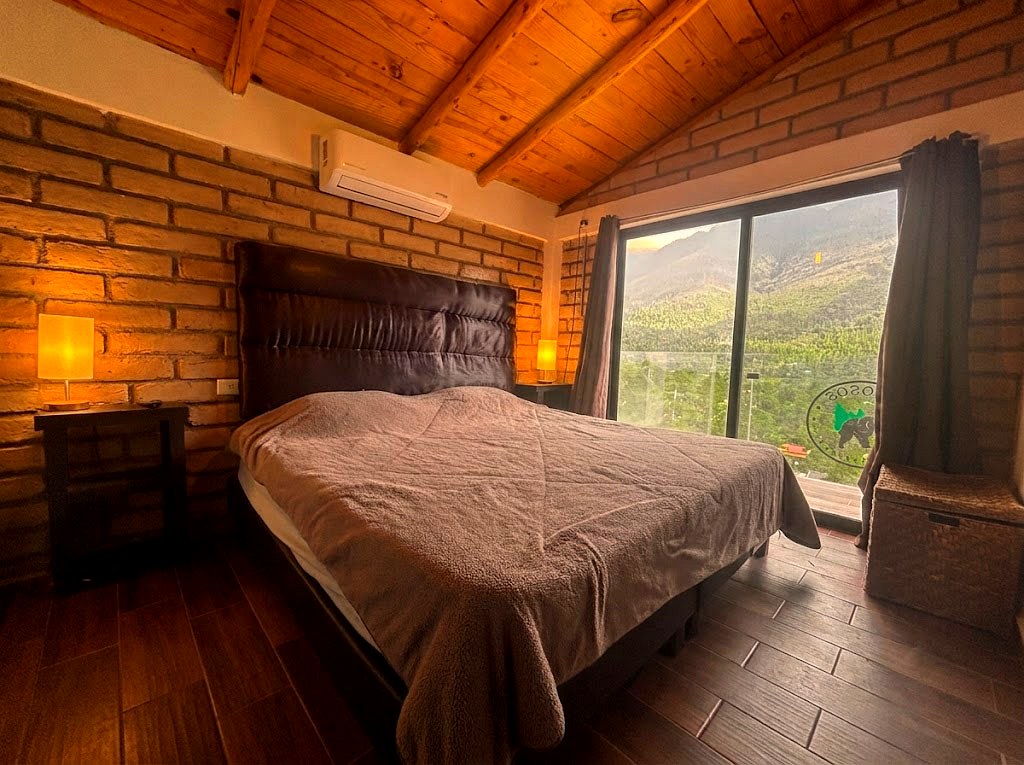 Segunda recámara de planta alta en OSA MAYOR con cama matrimonial y ventanal panorámico a la montaña