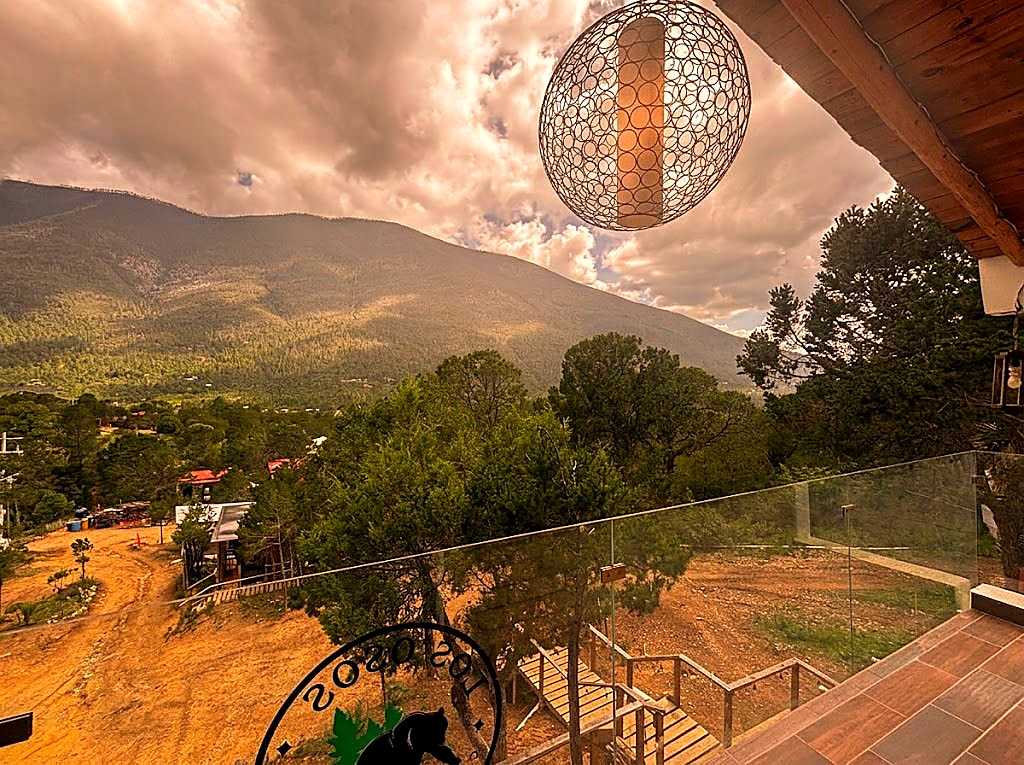 Vista panorámica desde la terraza de OSA MAYOR con lámpara esférica de diseño, montañas boscosas y cielo al atardecer