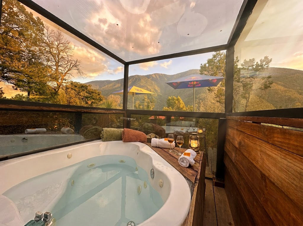 Jacuzzi privado de SIRIUS bajo domo de cristal con velas, copas de vino y vista al atardecer en las montañas