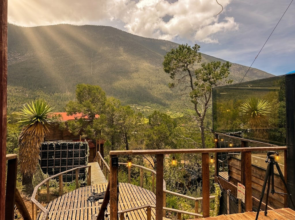 Terraza de SIRIUS al atardecer con luces cálidas, yucas y vista abierta a la montaña con rayos de sol filtrándose