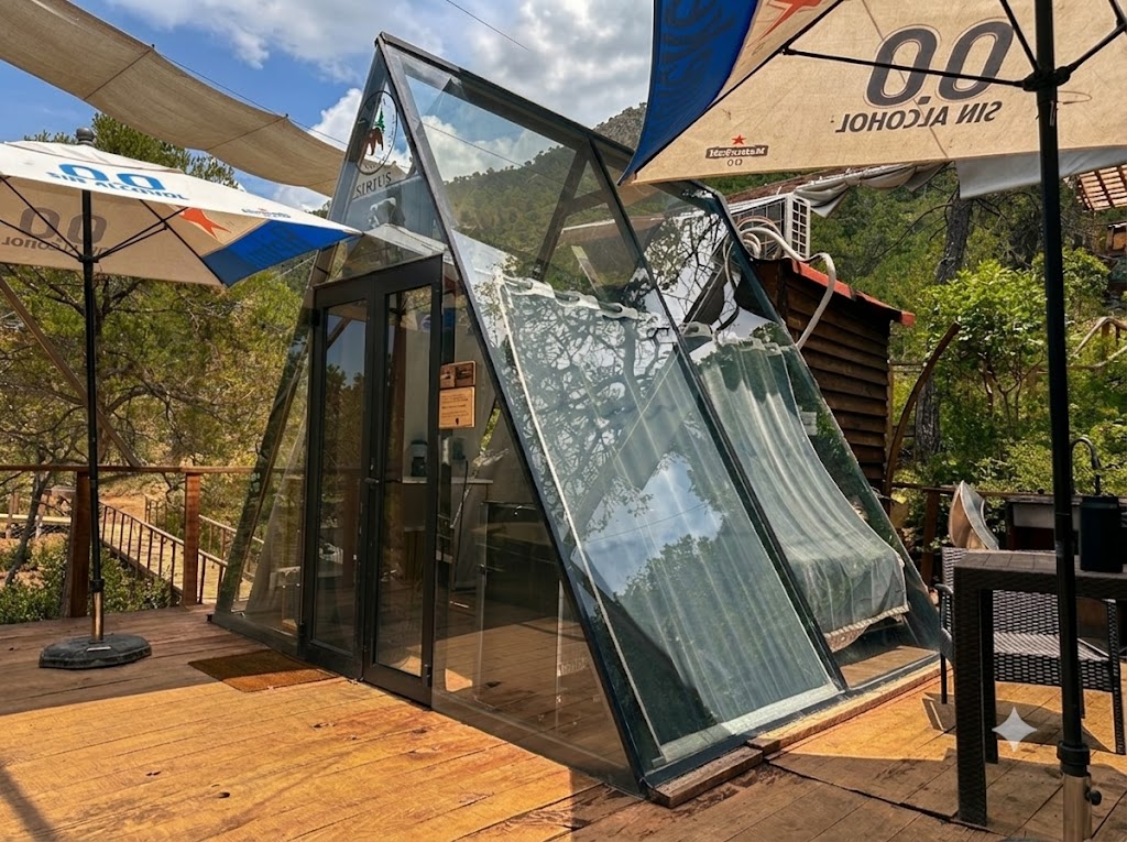 Exterior de SIRIUS con estructura A-frame de cristal, sombrillas y deck de madera entre los pinos de la Sierra de Arteaga
