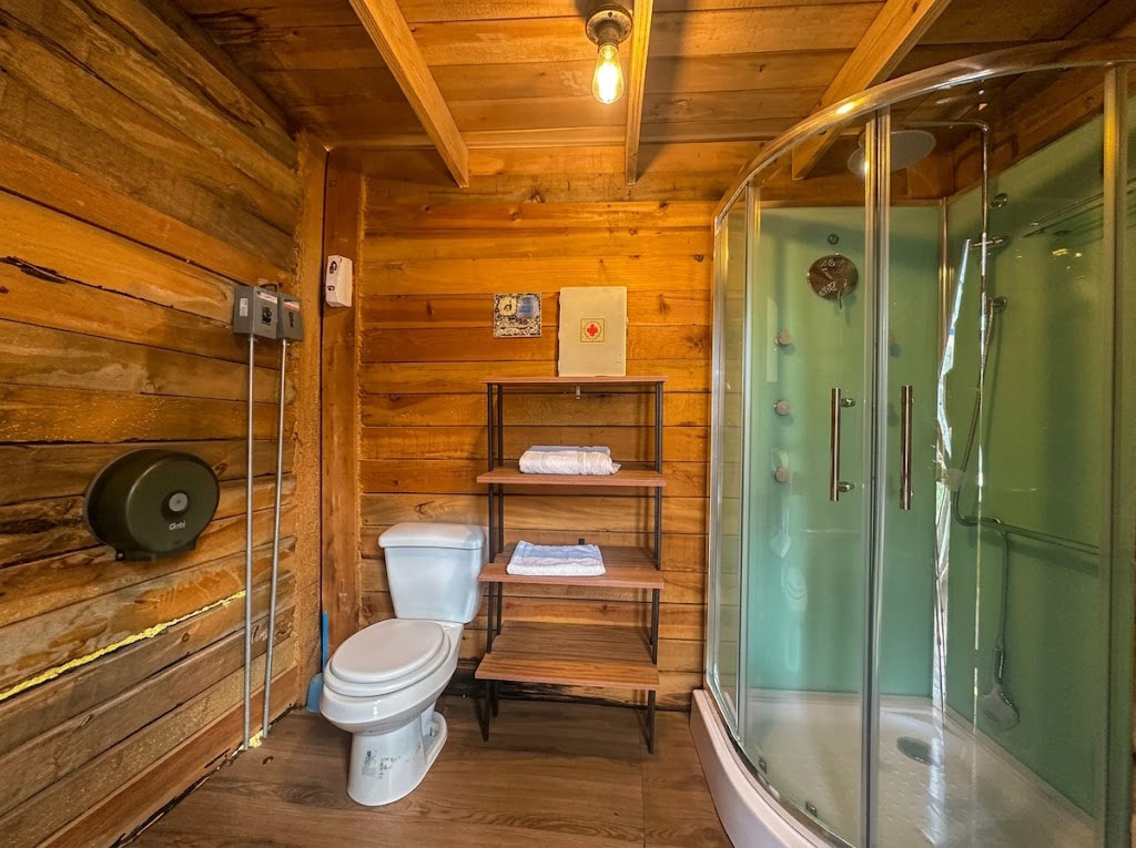 Baño completo de SIRIUS con regadera hidromasaje de cristal, sanitario y acabados en madera cálida
