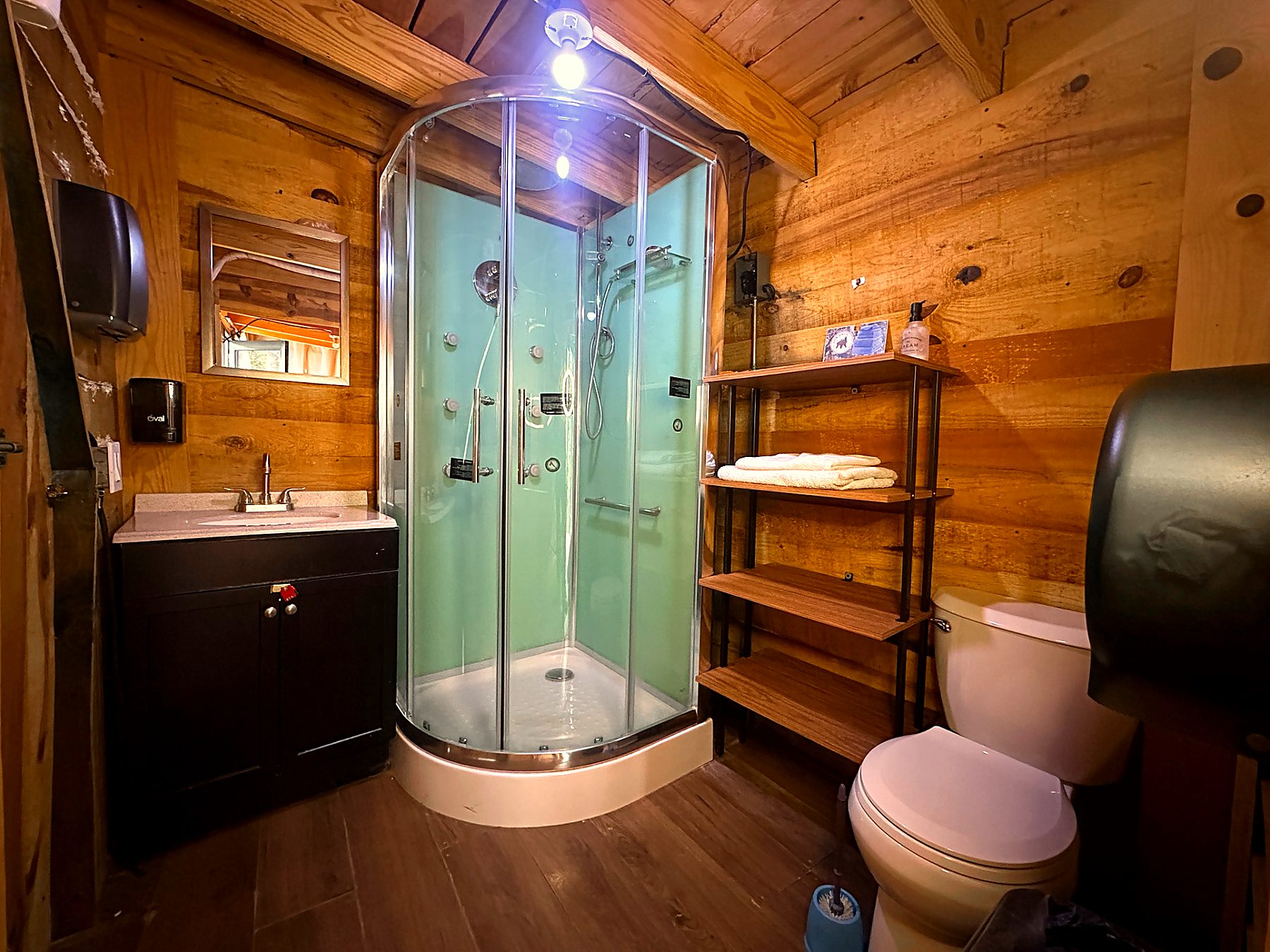Baño privado de AURORA BOREAL con regadera tipo hidromasaje, acabados en madera y toallas blancas