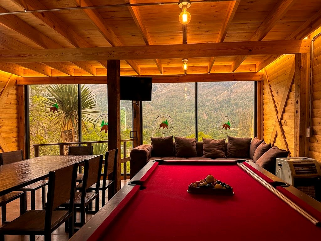Área de billar de ORION con mesa profesional, Smart TV y ventanales con vista al bosque de pinos