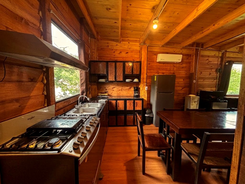 Cocina totalmente equipada de FENIX con estufa de seis quemadores, refrigerador, campana y ventanal al bosque
