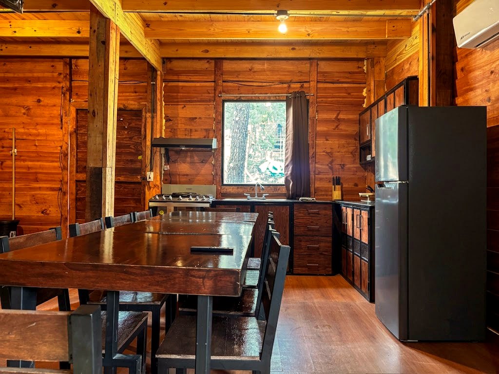 Comedor amplio de FENIX con mesa de madera maciza para ocho personas, cocina equipada y refrigerador