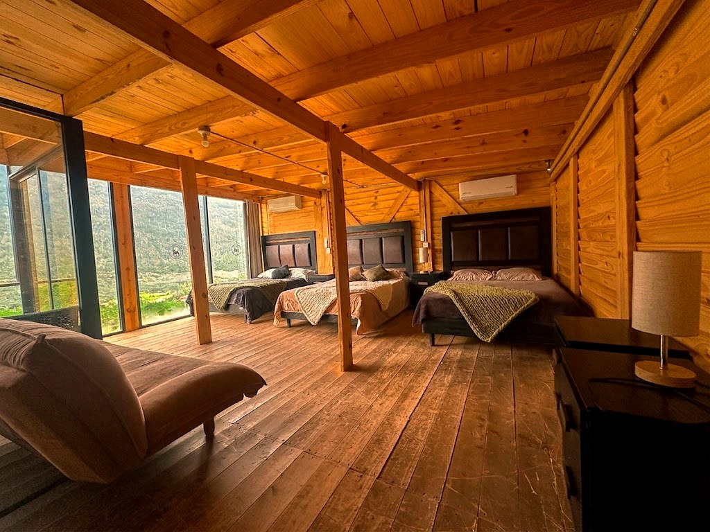 Recámara amplia de ORION con tres camas, chaise lounge y ventanal panorámico a la Sierra de Arteaga