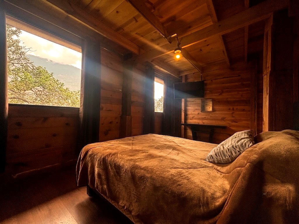 Recámara de FENIX con cama matrimonial, ventanal panorámico a las montañas y climatización
