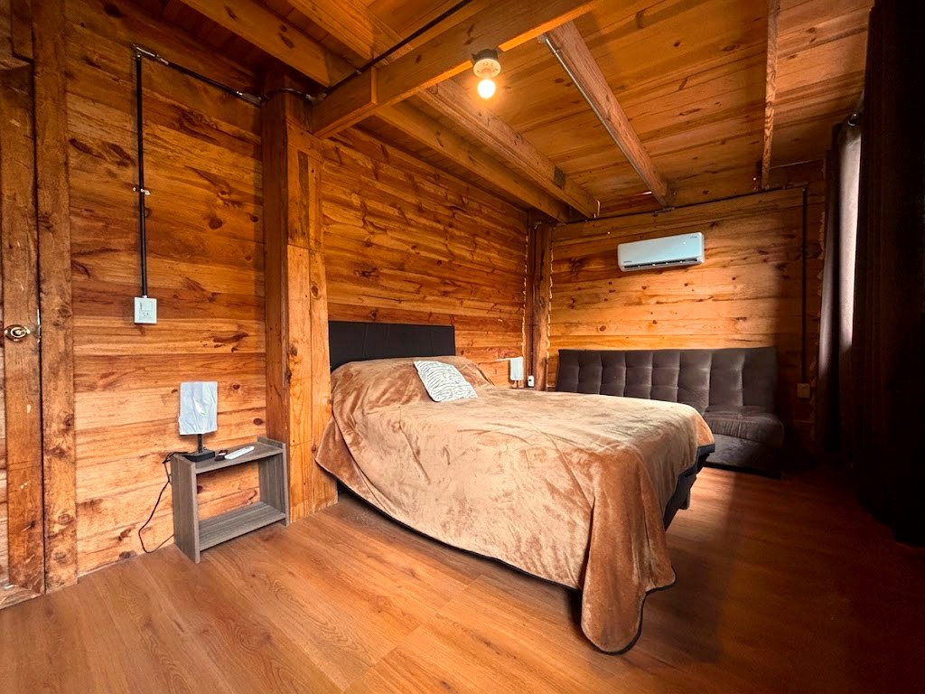 Tercera recámara de FENIX con cama king, sofá y acabados en madera cálida sobre piso laminado