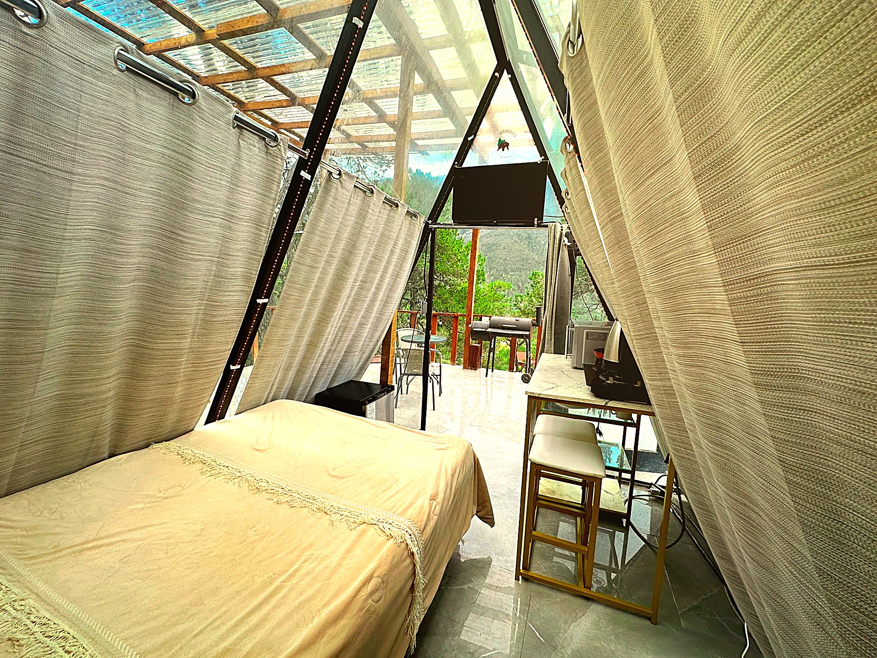 Interior de ATENEA con Smart TV, cocineta y salida directa a la terraza con vista al bosque