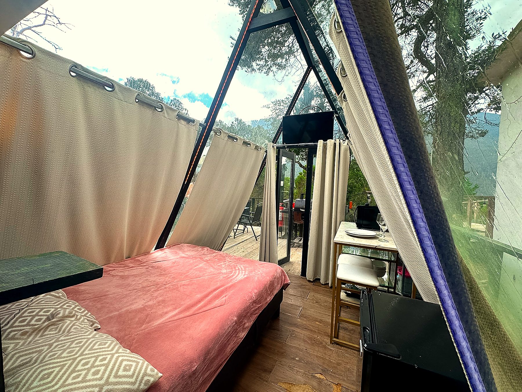 Interior de AURORA BOREAL con Smart TV, cocineta y salida directa a la terraza a través de los ventanales de cristal