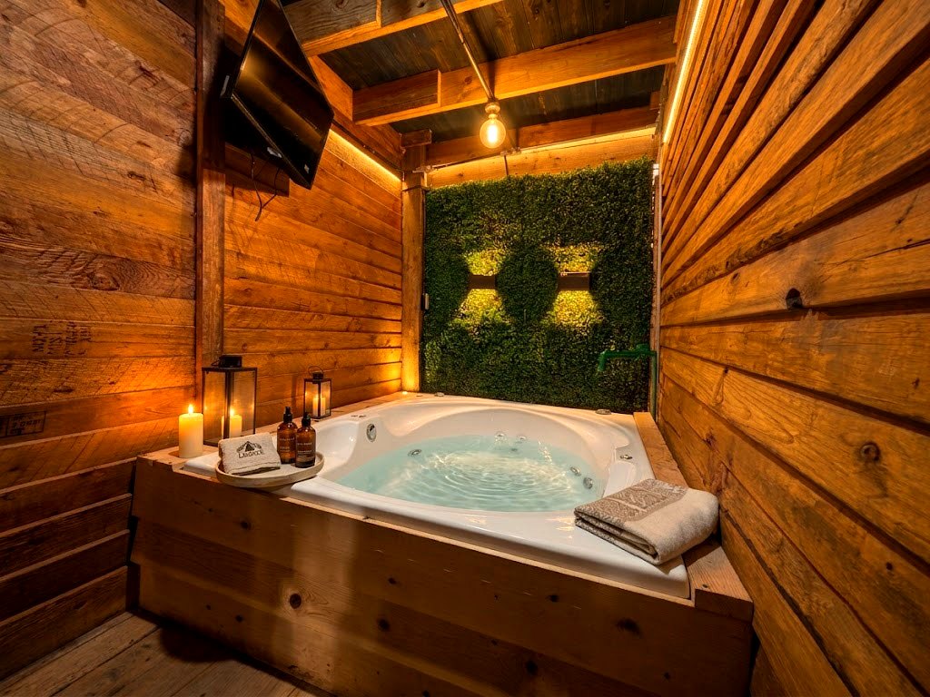 Jacuzzi privado de FENIX con muro verde vivo, iluminación LED cálida, velas y Smart TV bajo techo de madera