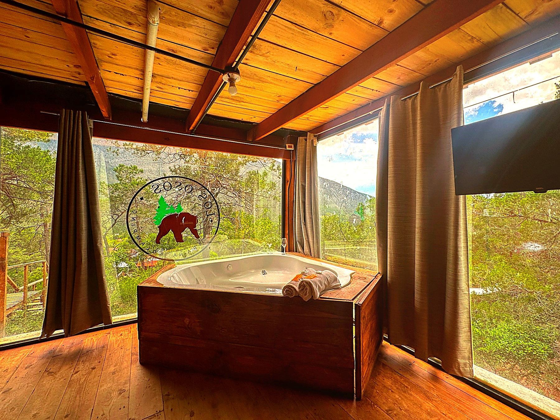 Jacuzzi privado de ATENEA rodeado de ventanales con vista panorámica a los pinos y la montaña