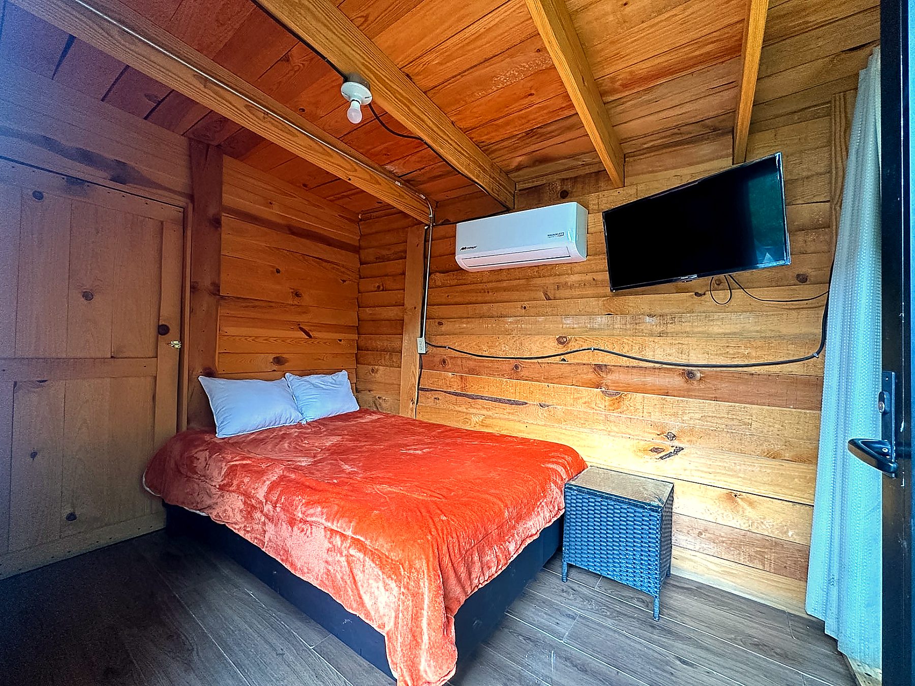Recámara acogedora de AURORA BOREAL con cama, muros de madera cálida, Smart TV y climatización