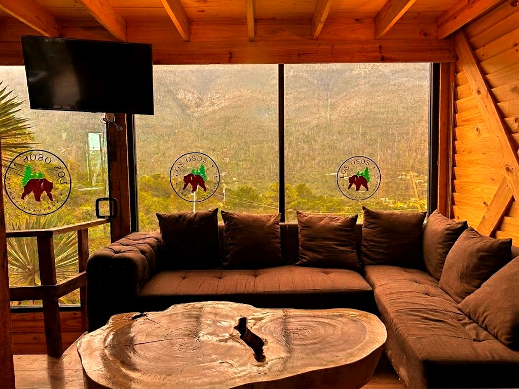 Estancia acogedora de ORION con sillón esquinero, cojines cálidos y ventanales panorámicos a las montañas