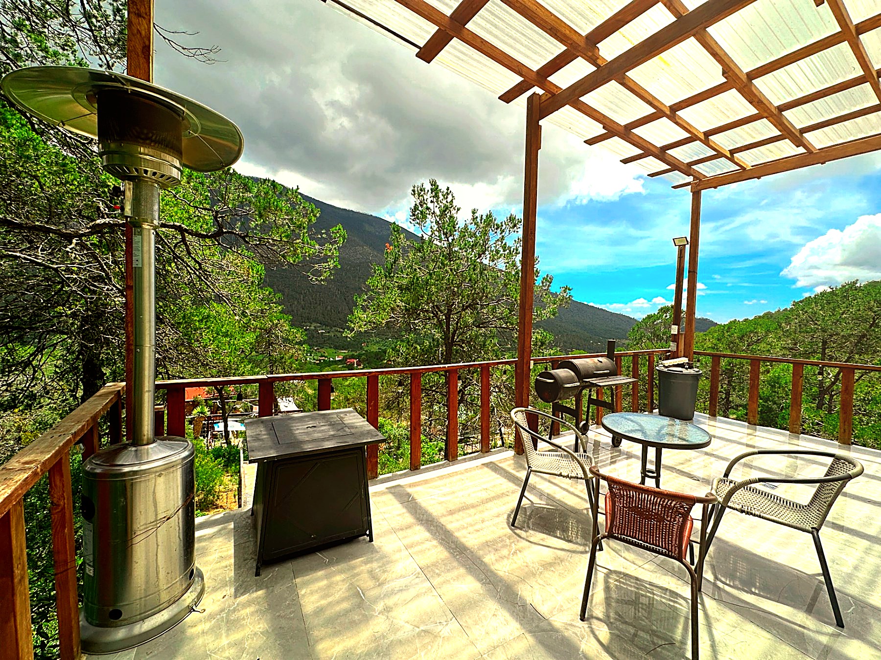 Terraza de ATENEA con calentador de patio, fogatero, asador y vista abierta al valle boscoso