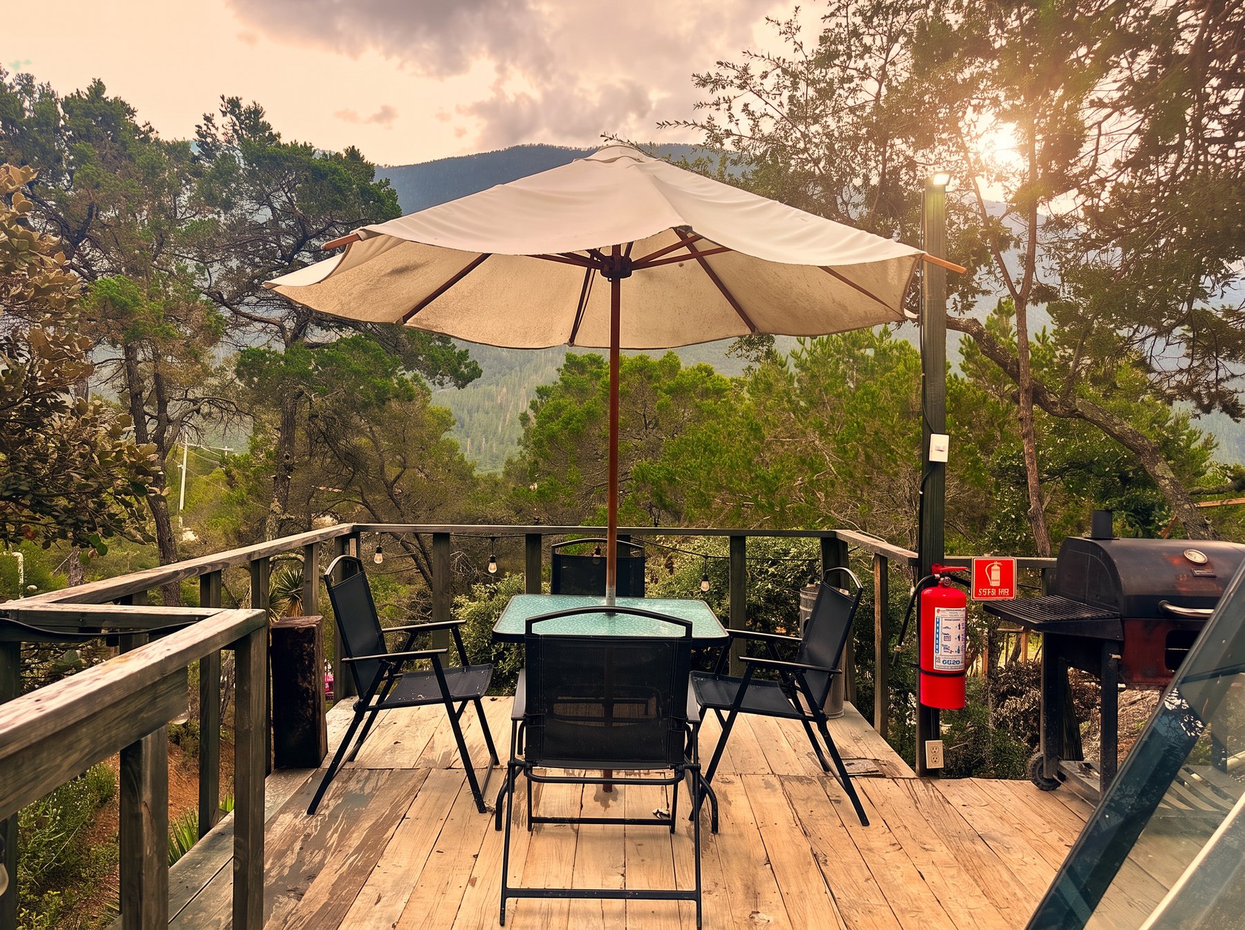 Terraza privada de AURORA BOREAL con mesa, sillas, sombrilla, asador y vista abierta a la montaña de la Sierra de Arteaga